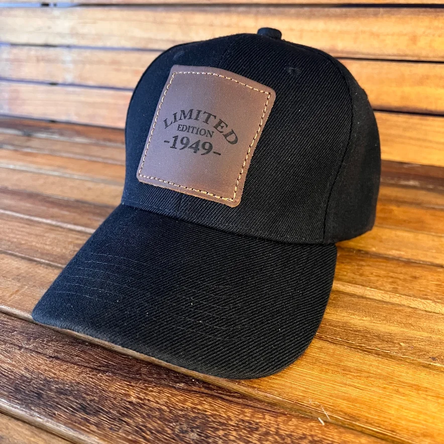 Gorra negra con parche de piel marrón grabado con "LIMITED EDITION -1949-" sobre una mesa de madera