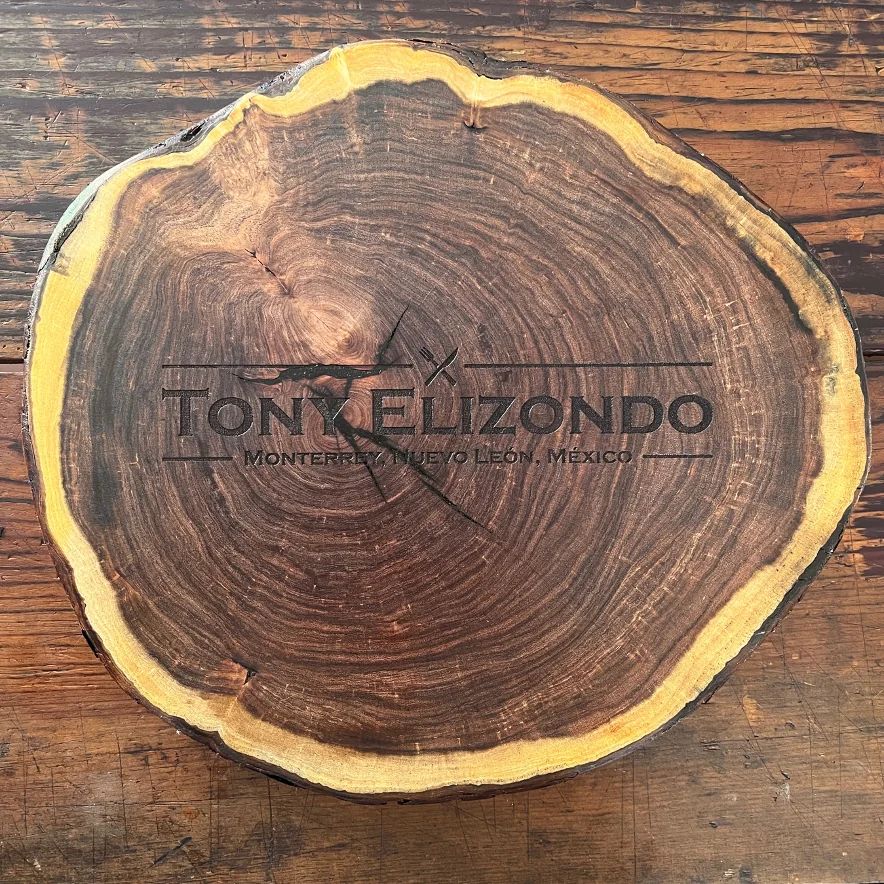 Tabla de madera oscura con corteza clara y el nombre 